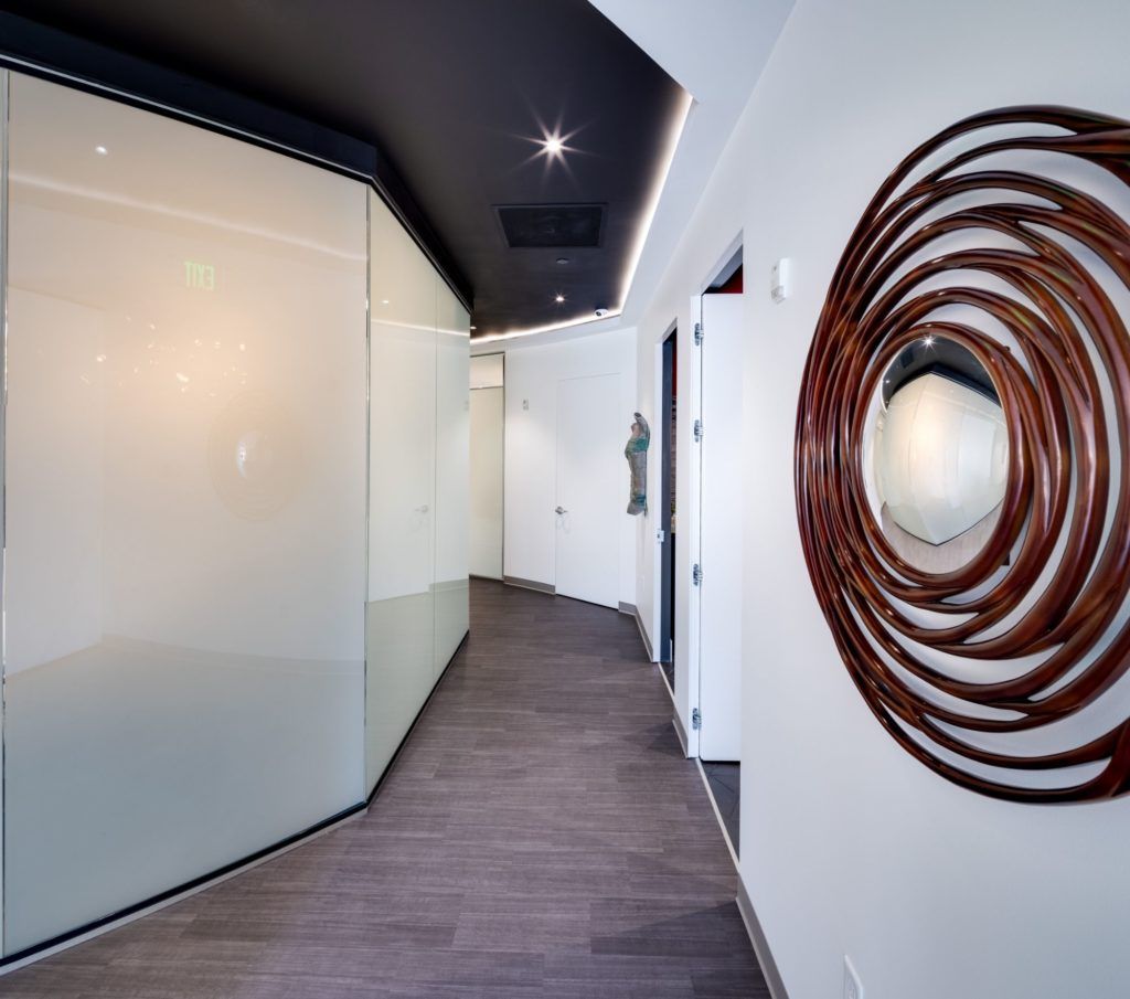 Modern hallway with curved glass and artistic decor.