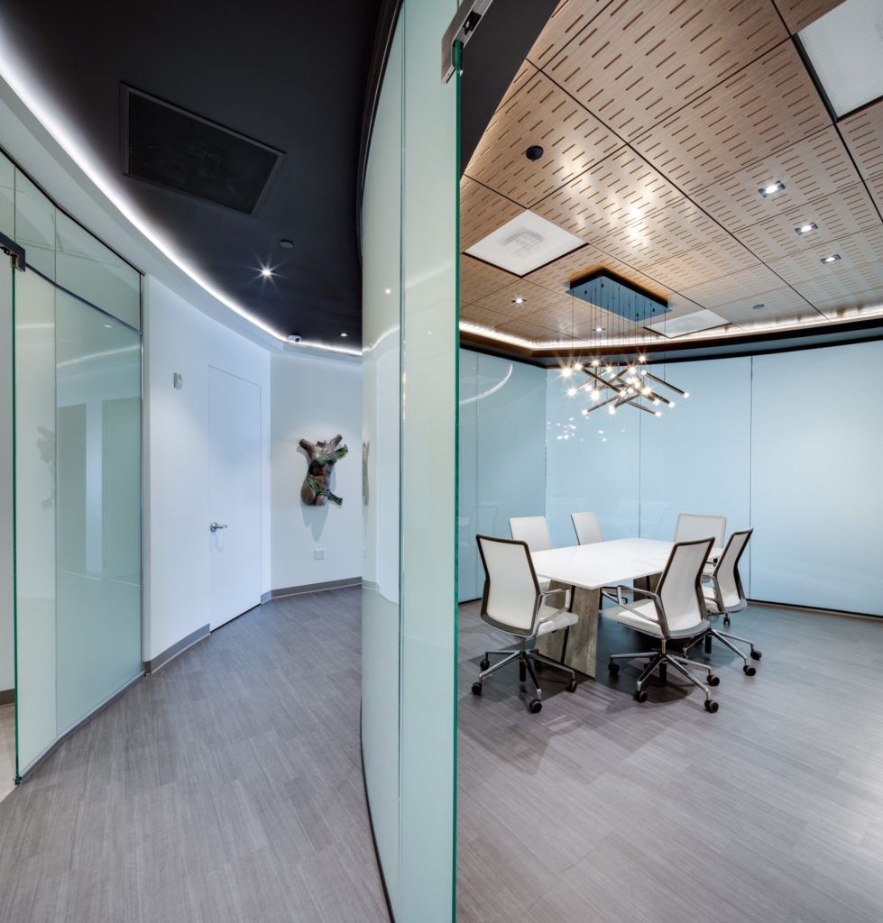 Modern office space with glass walls and furniture.