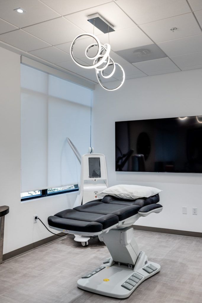 Modern medical room with examination chair and lighting.