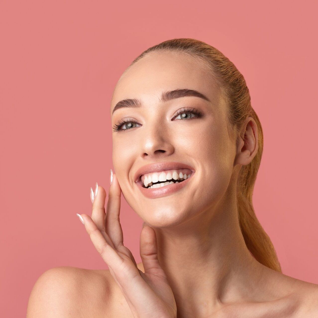 Smiling woman with beautiful skin on pink background.