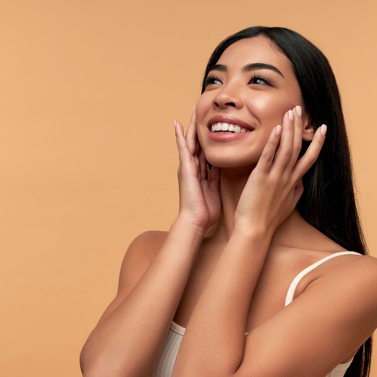 Smiling woman with long hair against orange background.