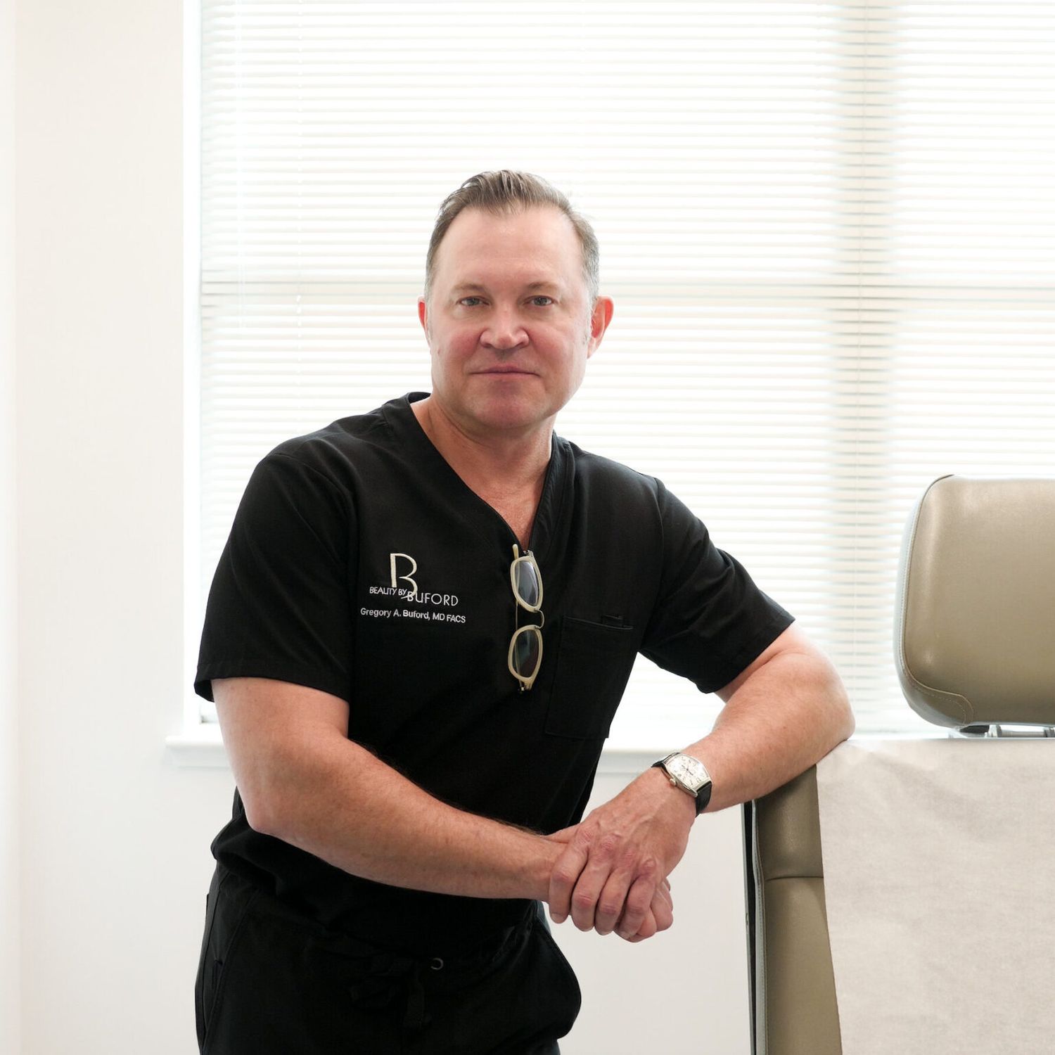 Doctor in medical office, wearing scrubs and glasses.