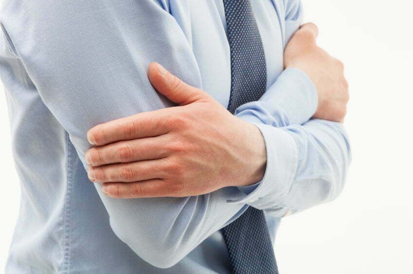 Man in a dress shirt crossing arms.