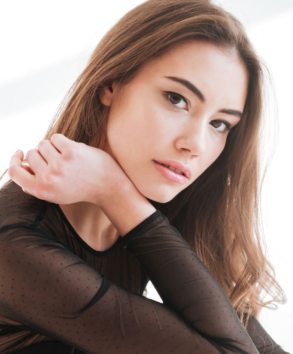 Woman in black bra gazing out window.