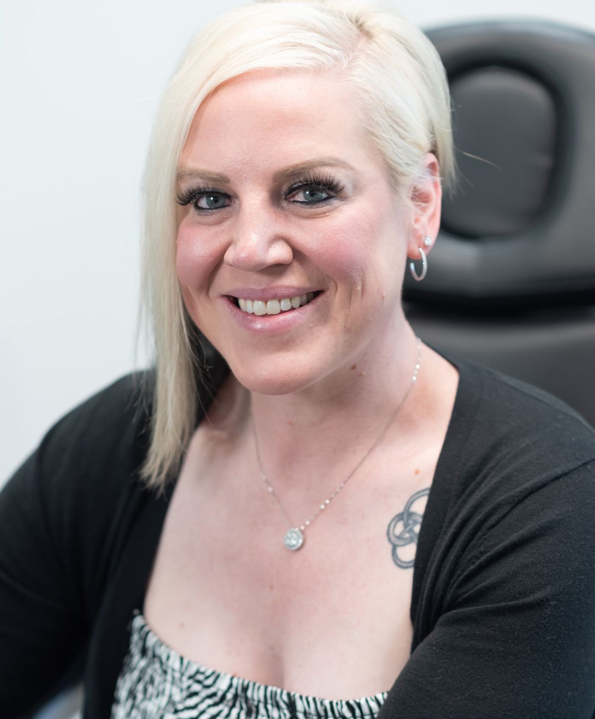 Smiling woman with short blonde hair and necklace.