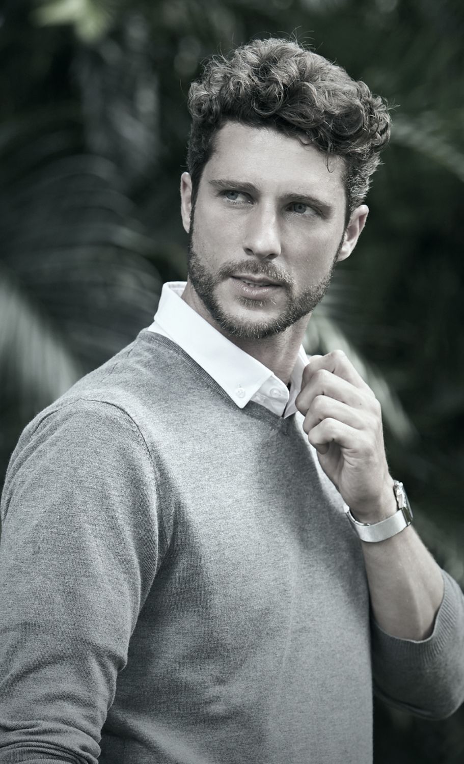 Denver plastic surgery male model in gray sweater adjusting collar outdoors.