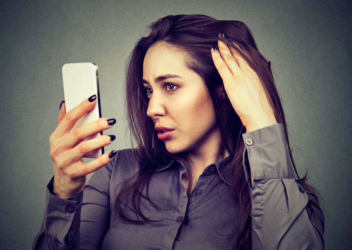 Woman using smartphone, looking concerned or thoughtful.