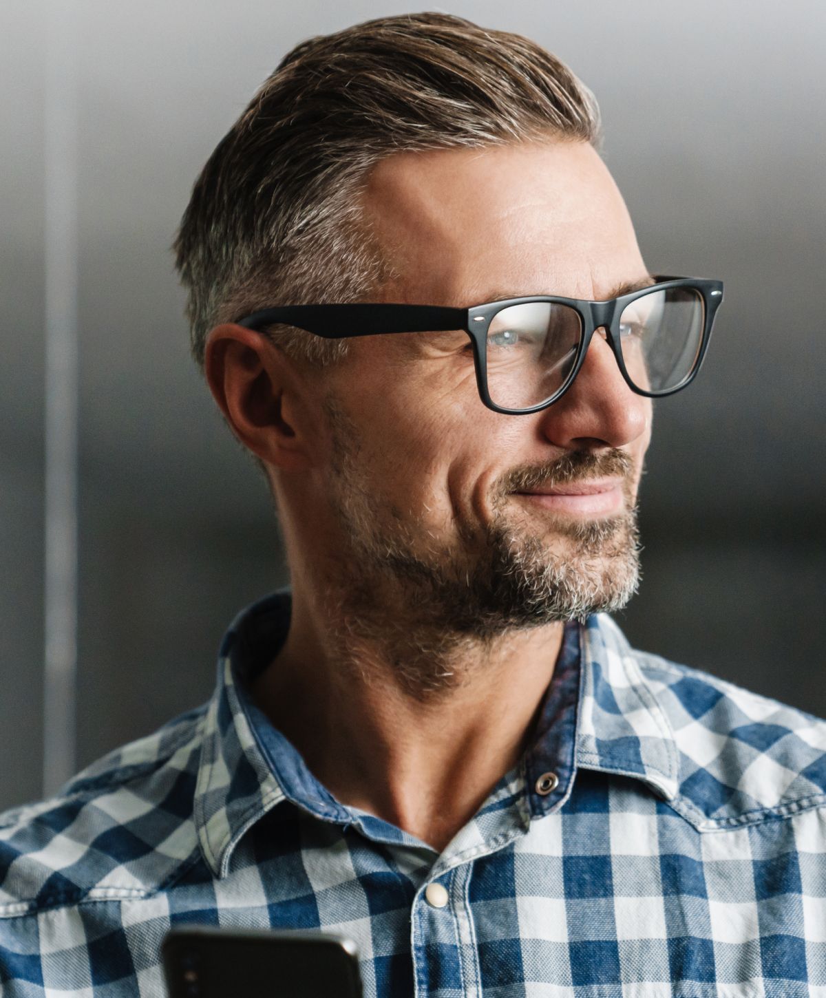 Man wearing glasses and plaid shirt, smiling.