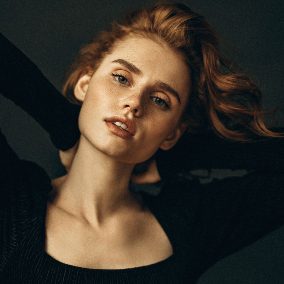 Denver med spa model with red hair posing against dark background.