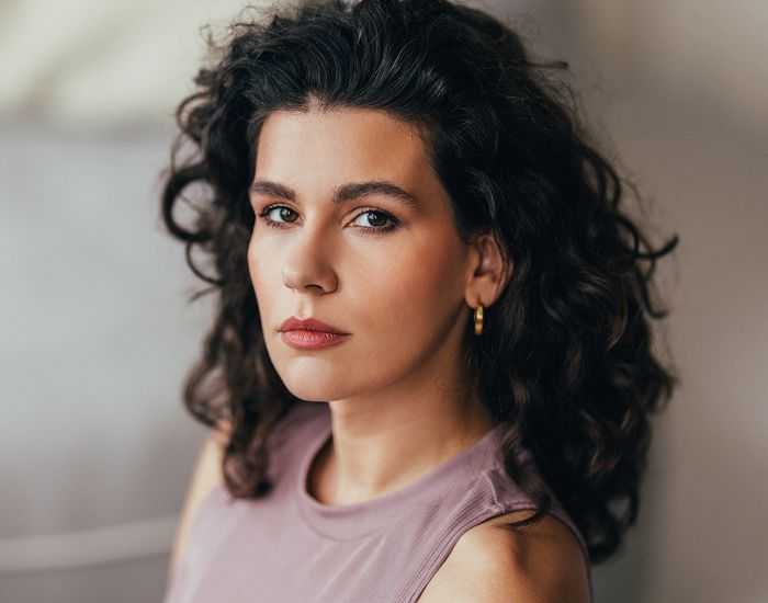 Woman smiling, holding "Hello Beautiful" sign.