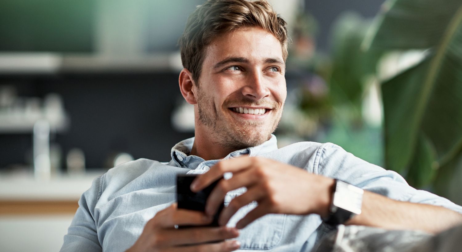 Young man sitting casually indoors, shirtless.