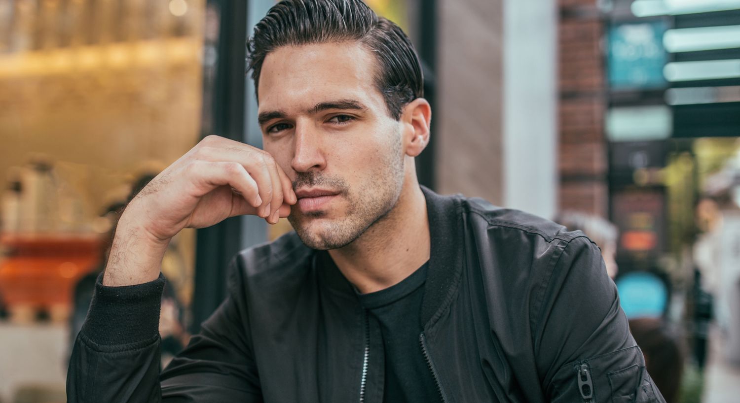 Man thoughtfully resting chin on hand outdoors.