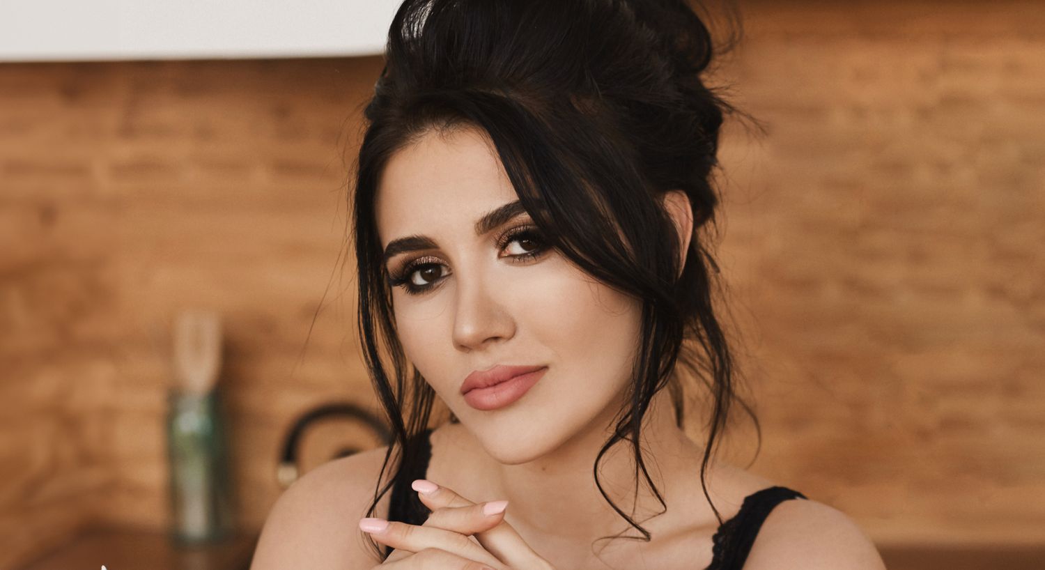 Woman posing in a warm wooden kitchen setting.