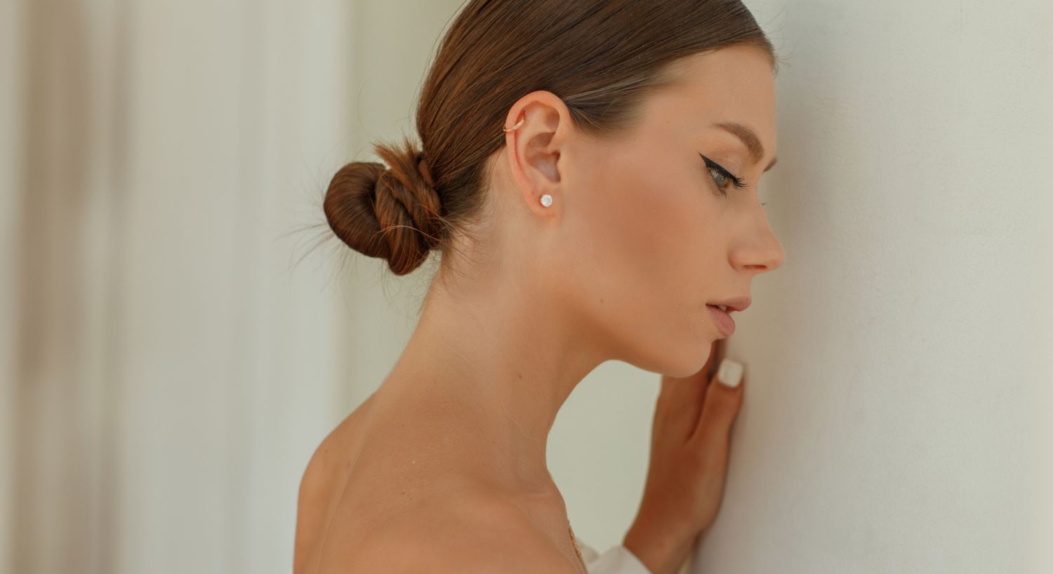 Profile of woman touching a white wall.